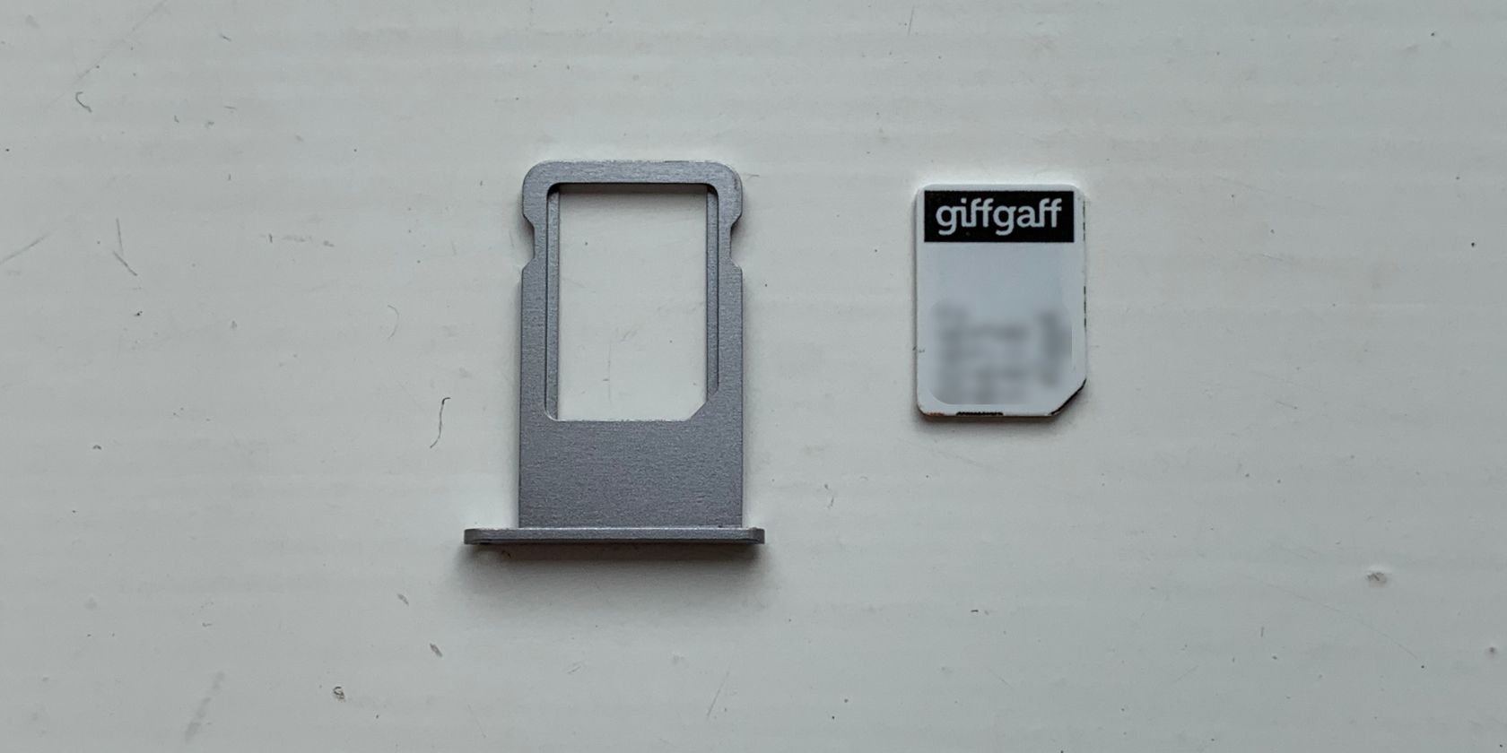 SIM card next to iPhone SIM tray - Come rimuovere una scheda SIM da un iPhone